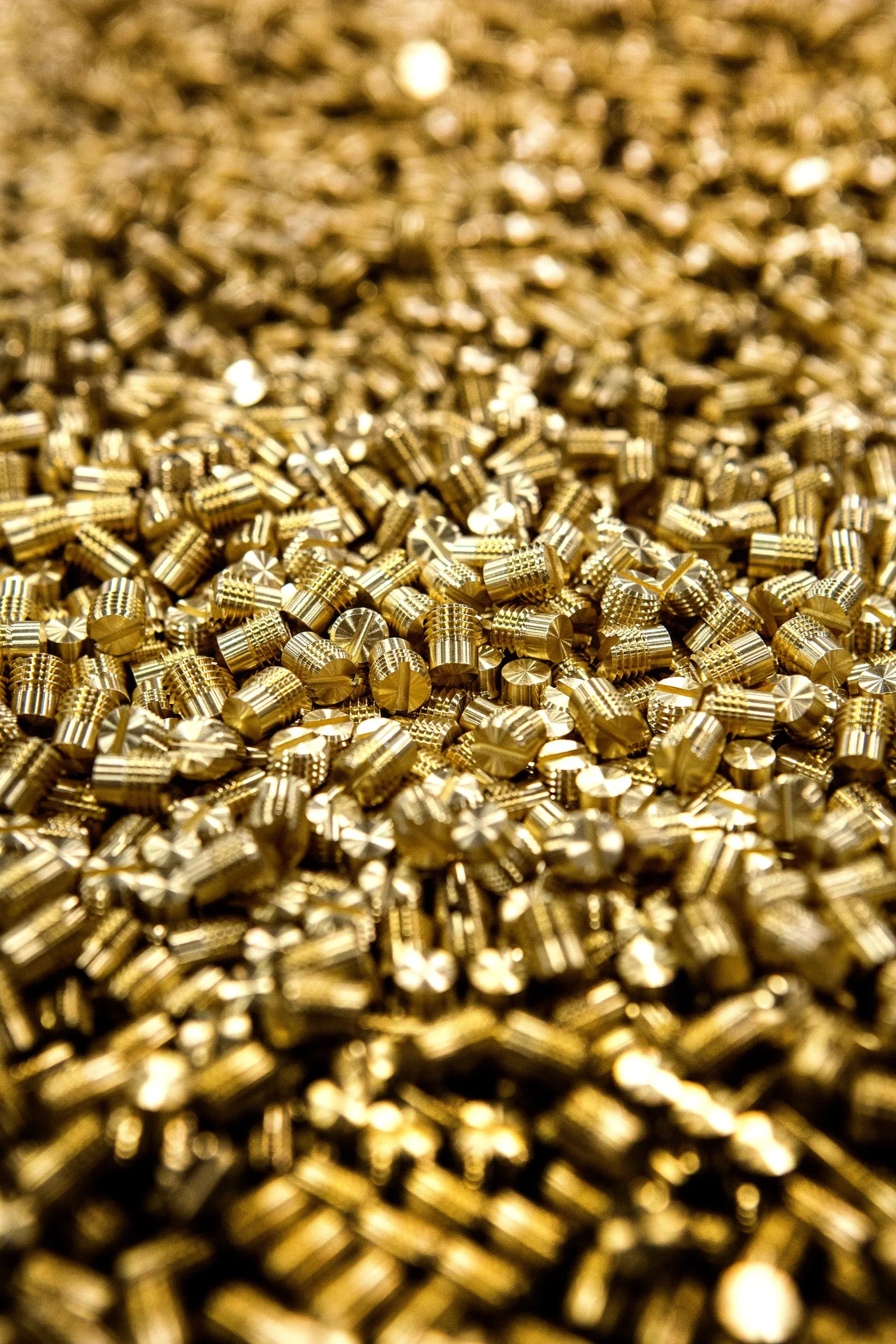 A heap of small threaded brass parts, vertical frame