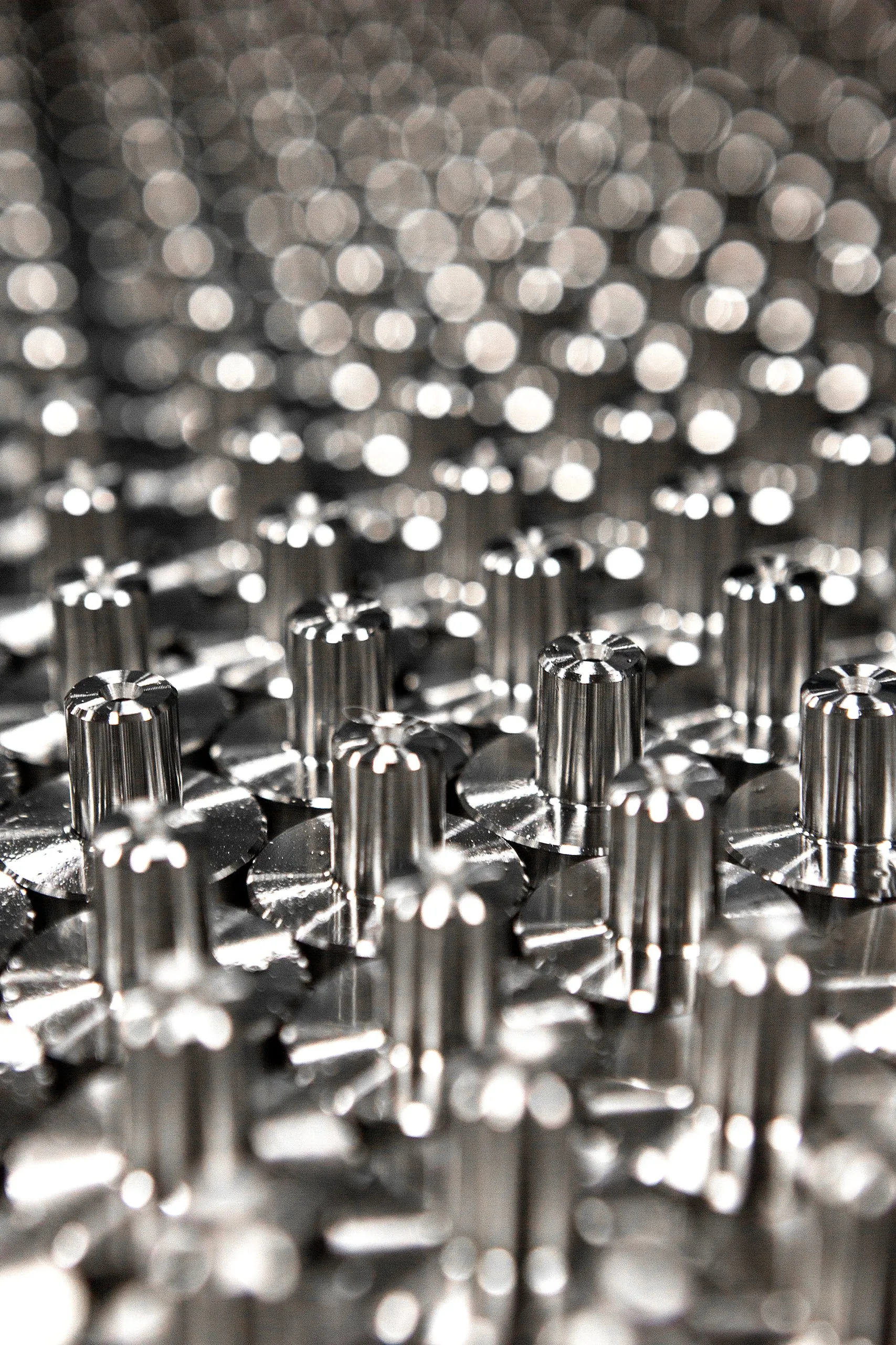 Rows of small machined steel parts standing on end, in shallow focus