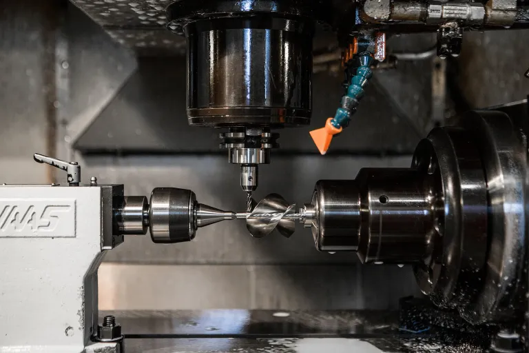 A drill held in a CNC machine, aligned with a part in the chuck