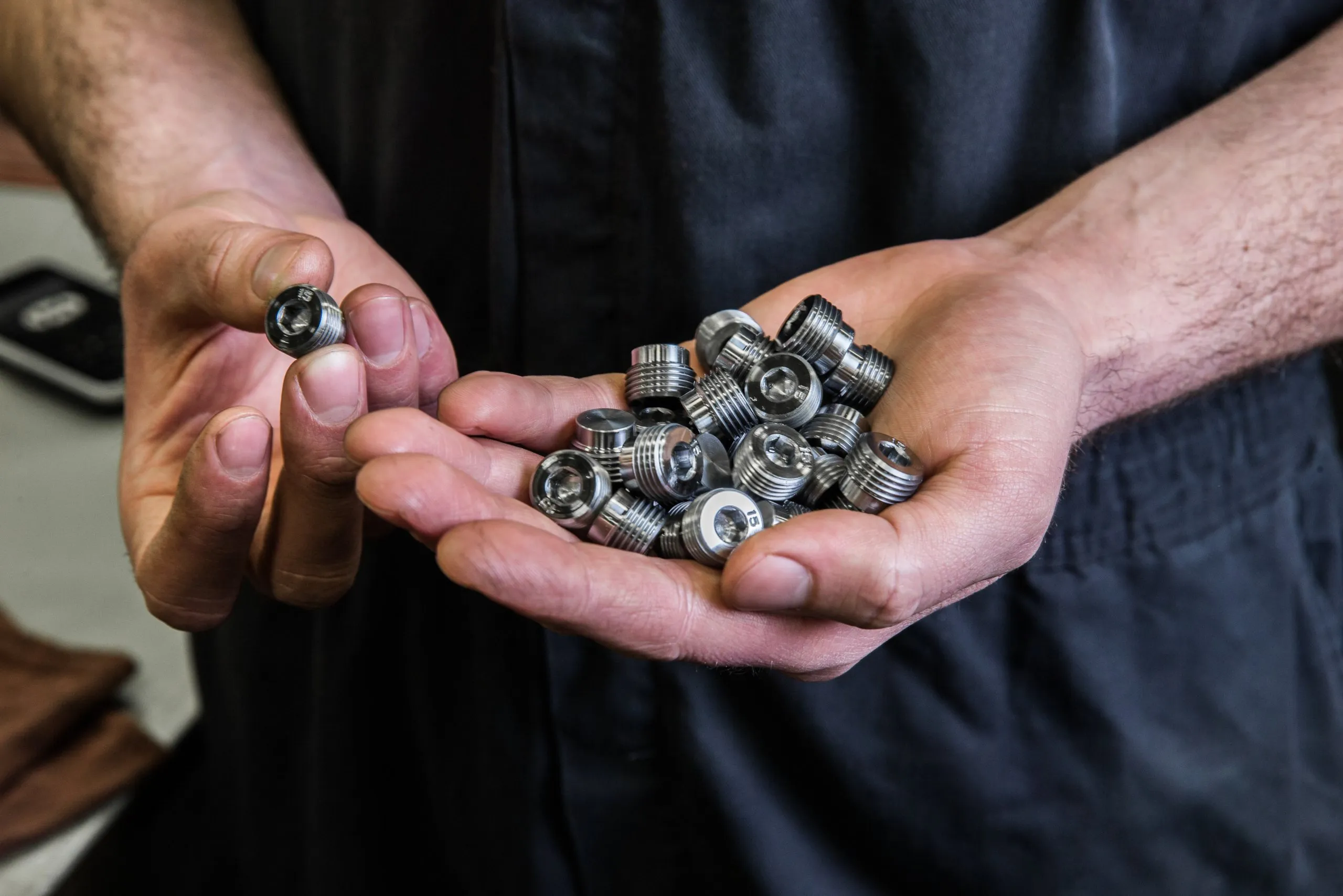 Cupped hands holding a pile of small machined parts