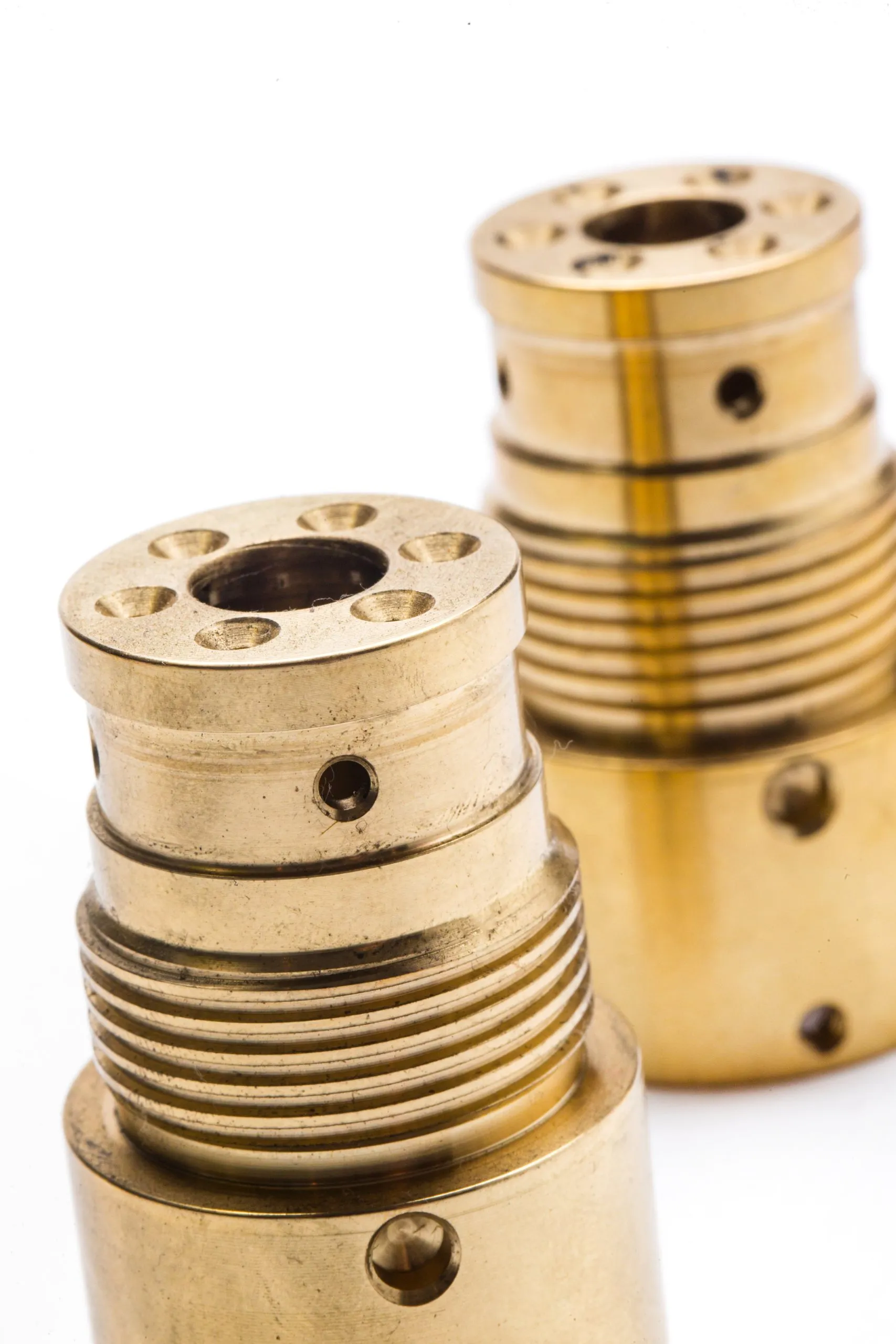 Threaded brass parts standing upright on white
